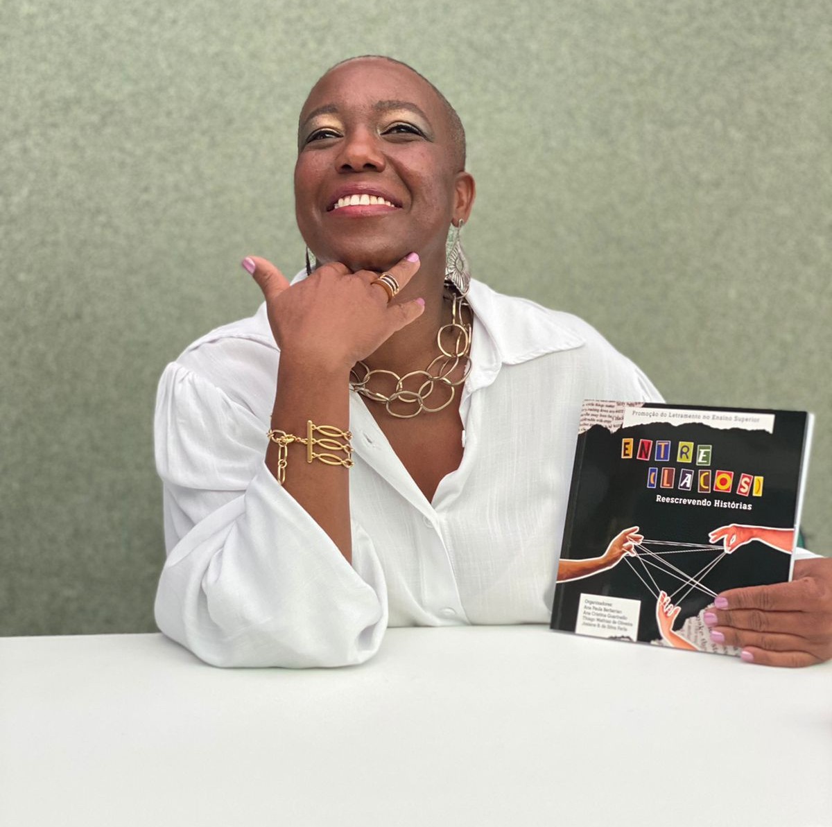 Fono Clau segurando livro publicado com sua participação